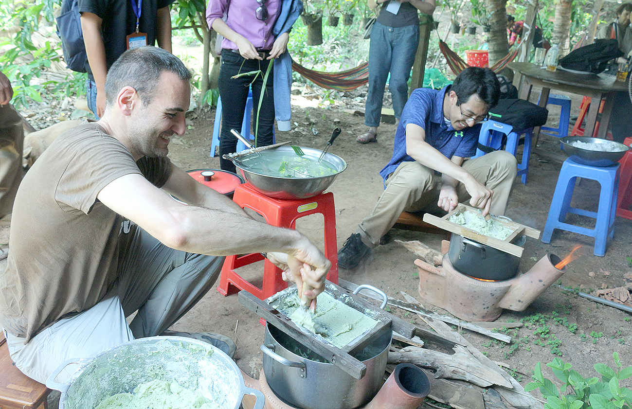 Foreign tourists eargerly make sweet rice pasta dessert.