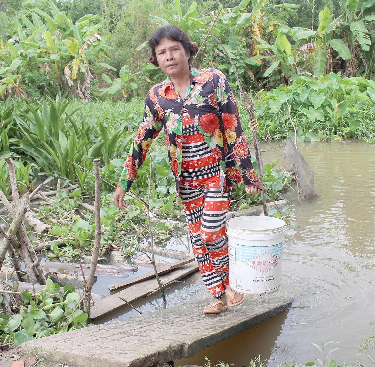 Hằng ngày, bà Trần Thị Minh phải canh nước lớn để xách nước dưới rạch Ngọn Khoán Châu lóng phèn sử dụng.