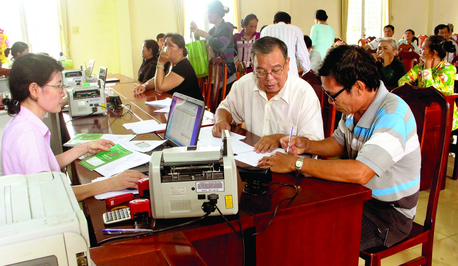 Giao dịch viên Phòng Giao dịch NHCSXH quận Bình Thủy phát vay cho các hộ mới thoát nghèo của phường Long Hòa, quận Bình Thủy.