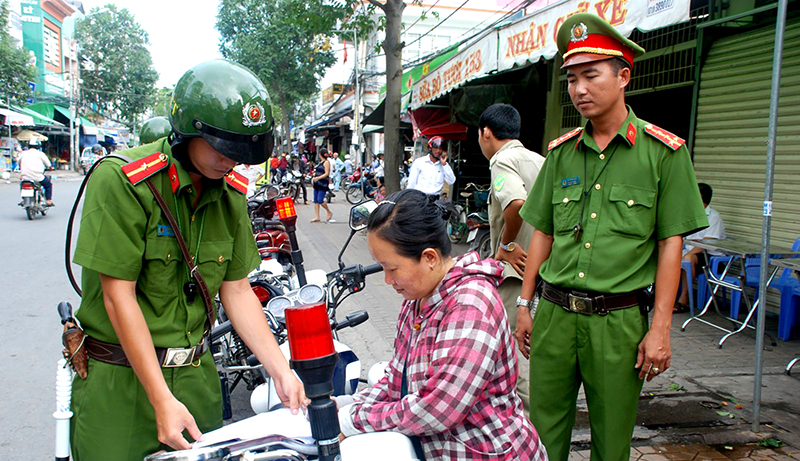 Cảnh sát trật tự Công an quận Ninh Kiều tuyên truyền, vận động các tiểu thương trên đường Trần Việt Châu ký cam kết chấp hành Luật Giao thông đường bộ và trật tự đô thị. Ảnh: TRẦN VŨ TRỌNG
