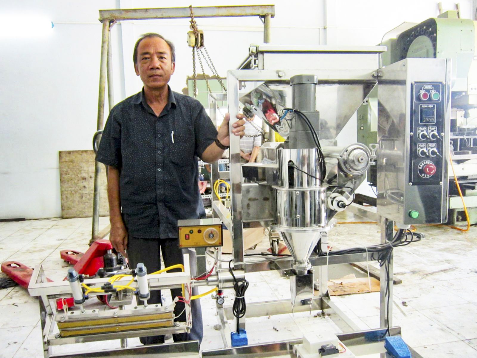 Ông Thái Mạnh Hùng bên  máy định lượng bột do ông nghiên cứu, chế tạo. Ảnh: LỆ THU