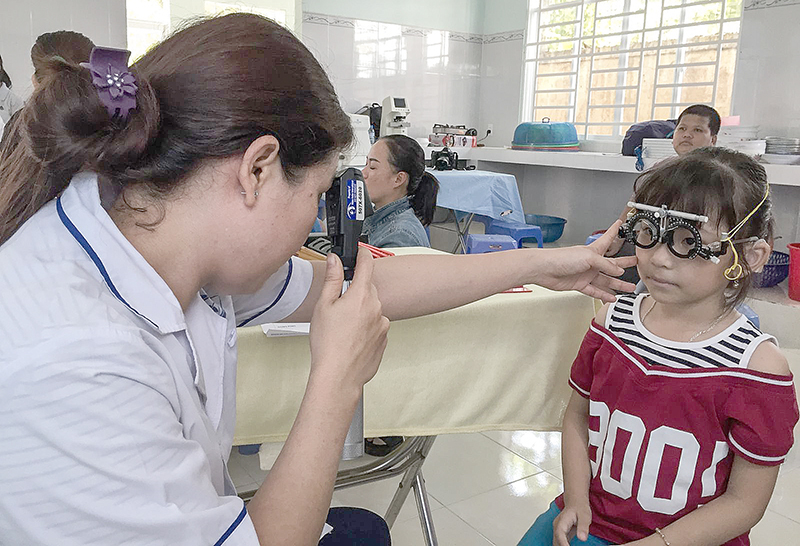 Cán bộ y tế khám mắt cho học sinh Trường Dạy trẻ khuyết tật Cần Thơ. Ảnh: H.HOA