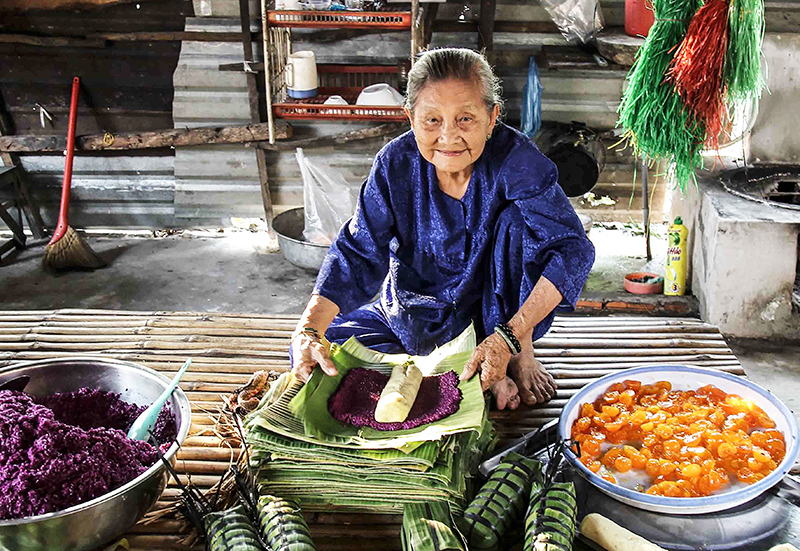 Nghệ nhân Huỳnh Thị Trọng gói bánh tét lá cẩm. Ảnh: ĐĂNG HUỲNH