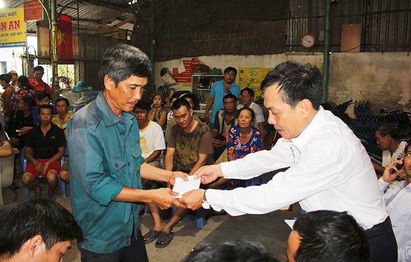 Ông Nguyễn Ngọc Hè (bên phải) trao tiền hỗ trợ cho hộ dân bị ảnh hưởng sạt lở. Ảnh: H.VĂN