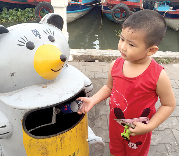 Nêu gương tốt cho con Phụ huynh dạy con bỏ rác vào thùng. Ảnh: ĐAN NHƯ