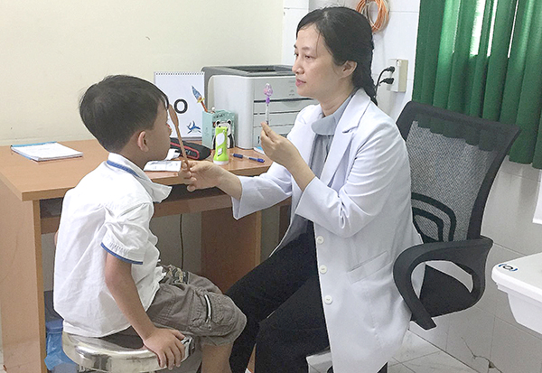 Bác sĩ Đường Thị Anh Thơ khám mắt cho trẻ bị lé. Ảnh: H.HOA