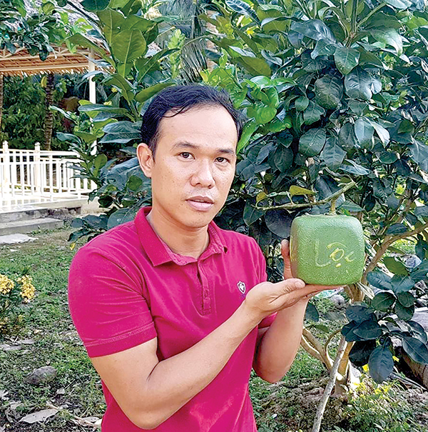 Anh Huỳnh Thanh Tâm bên sản phẩm trái cây tạo hình của mình. Ảnh: T.C