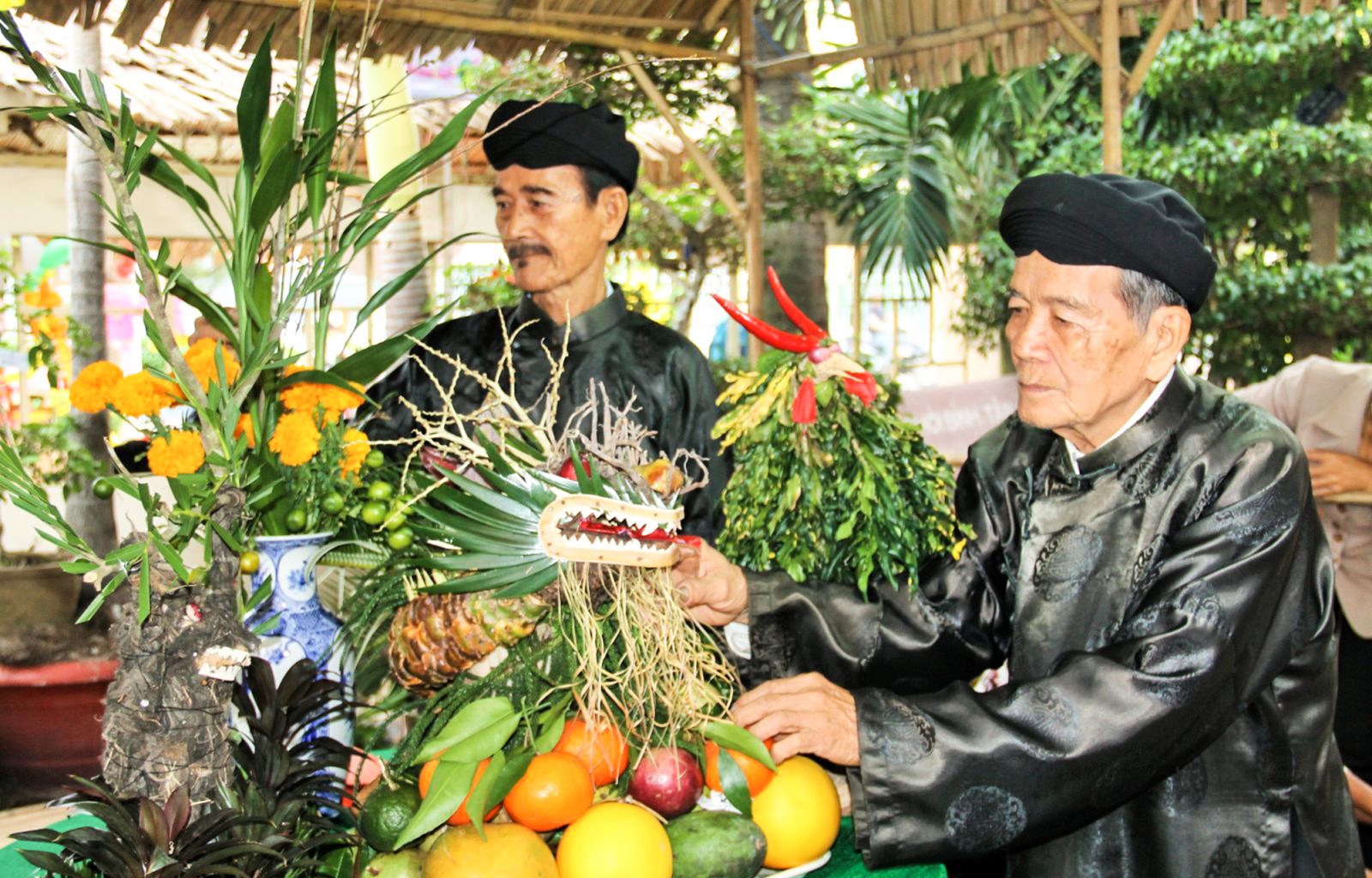 Ông Chín Hoằng (phải) và ông Năm Mới trình diễn trưng bày mâm trái cây, hoa quả ngày Tết tại chương trình “Sắc xuân miệt vườn”. Ảnh: ĐĂNG HUỲNH