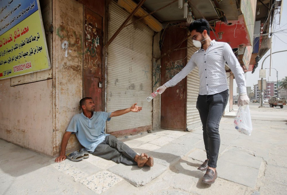 Một nhà hảo tâm trao nước uống cho người vô gia cư ở Iraq. Ảnh: Reuters