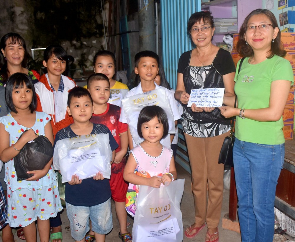 Chị Phạm Huỳnh Trang (bìa phải) trao tiền và quà cho cô trò lớp học tình thương tại phường An Cư, quận Ninh Kiều.