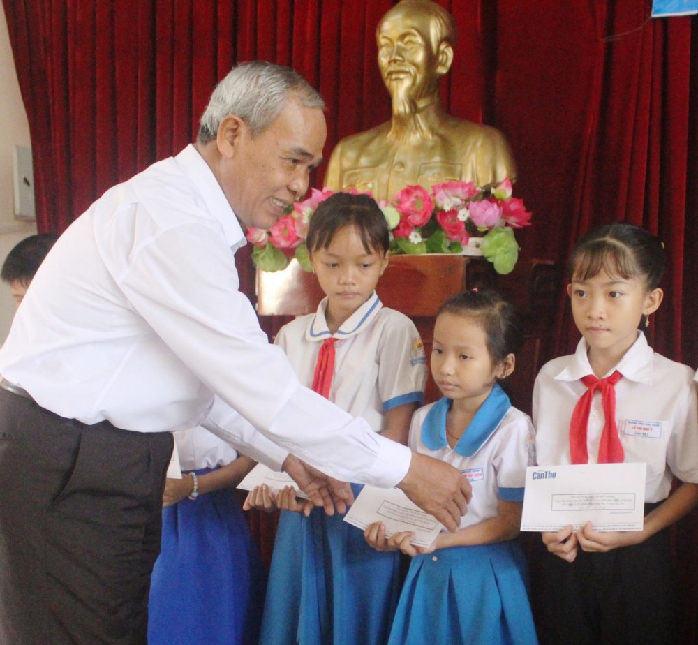 Ông Thạch Khên, nguyên Phó Tổng Biên tập Báo Cần Thơ, trao học bổng cho các em học sinh.