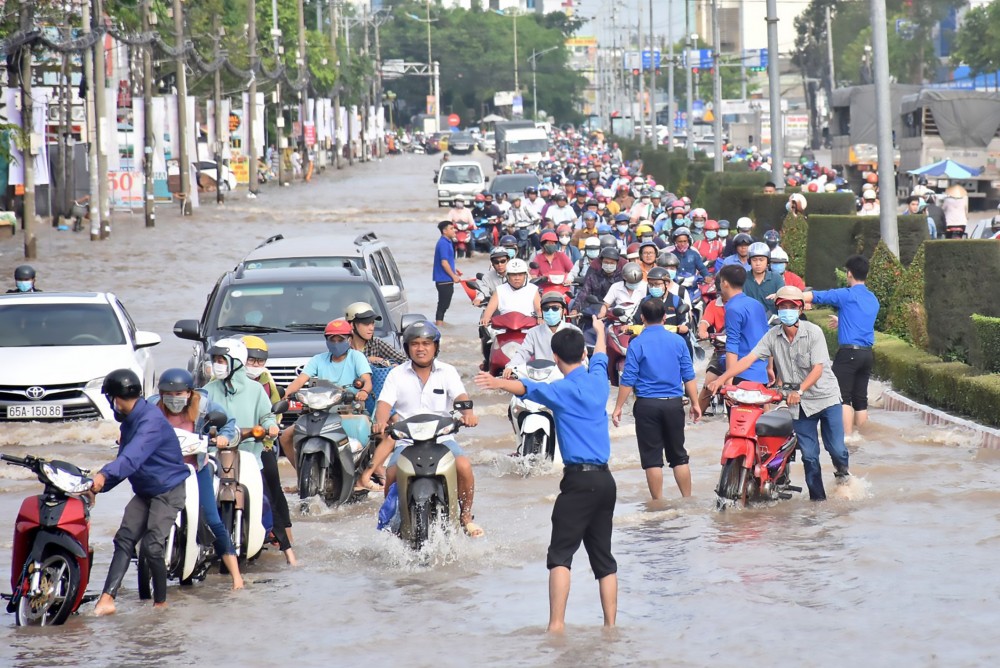 Các tình nguyện viên trực tiếp hướng dẫn người điều khiển xe khi triều cường dâng cao trên đường Mậu Thân.