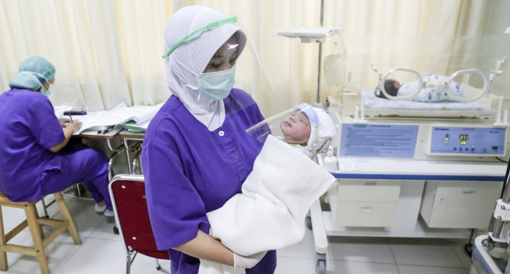 Y tá một bệnh viện ở thủ đô Jakarta chăm sóc trẻ sơ sinh. Ảnh: Bloomberg