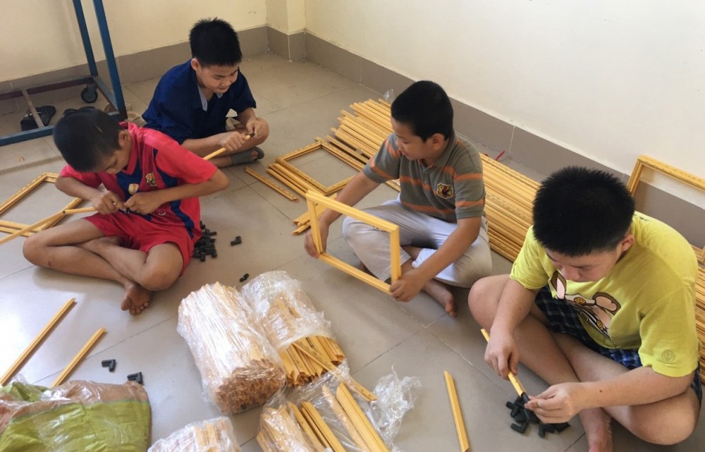 Trẻ có HCĐB tập trung thực hành nghề làm khung hình. Ảnh: CTV