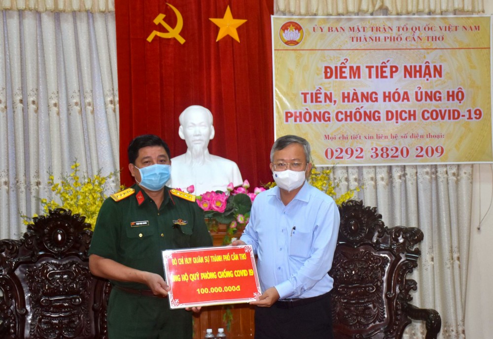 Đại tá Phạm Ngọc Quang (bên trái), Chính ủy - Bộ Chỉ huy Quân sự TP Cần Thơ, trao số tiền của cán bộ, chiến sĩ lực lượng vũ trang thành phố gởi ủng hộ công tác phòng, chống dịch COVID-19.