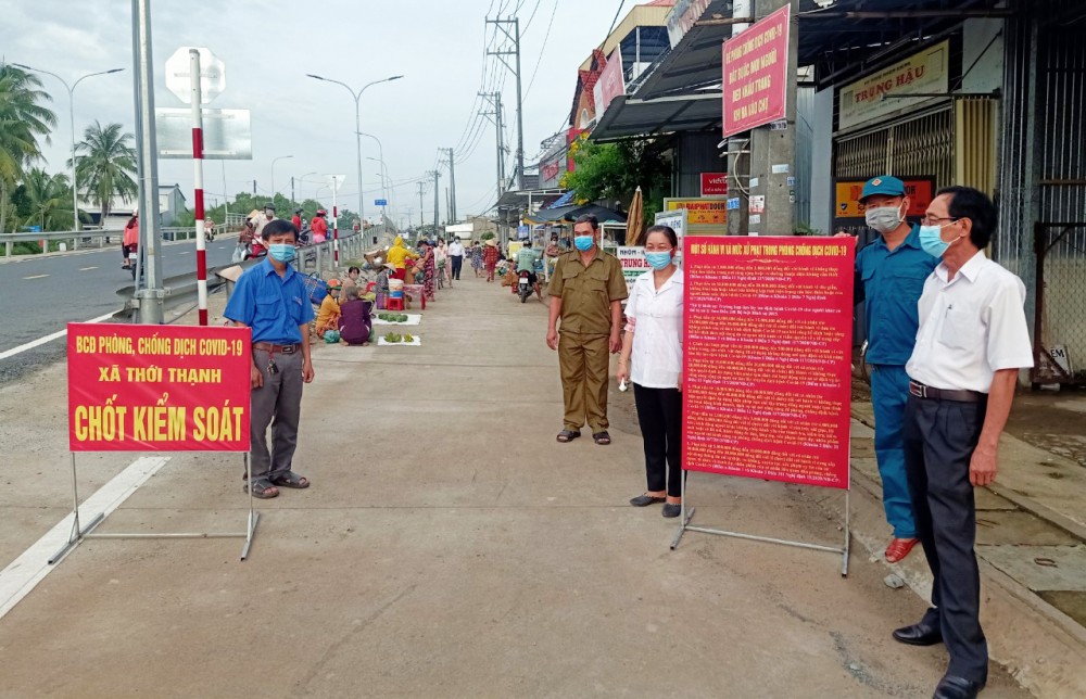 Bí thư Xã đoàn năng động Anh Nguyễn Trung Huấn (bên trái) tham gia kiểm soát và kiểm tra thân nhiệt những người vào chợ Rạch Tra.