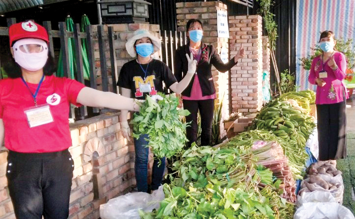 Chị Cẩm Vân (bên phải) tham gia cấp phát thực phẩm, rau củ cho người dân tại “Chợ 0 đồng”. Ảnh: CTV