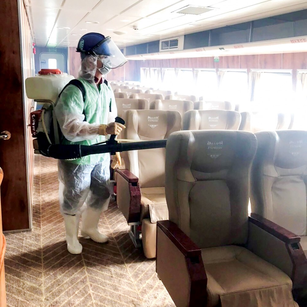 Nhân viên Công ty TNHH Dịch vụ vệ sinh Gia Nguyễn phun xịt khử trùng các xe khách của Công ty CP Tập đoàn Mai Linh.