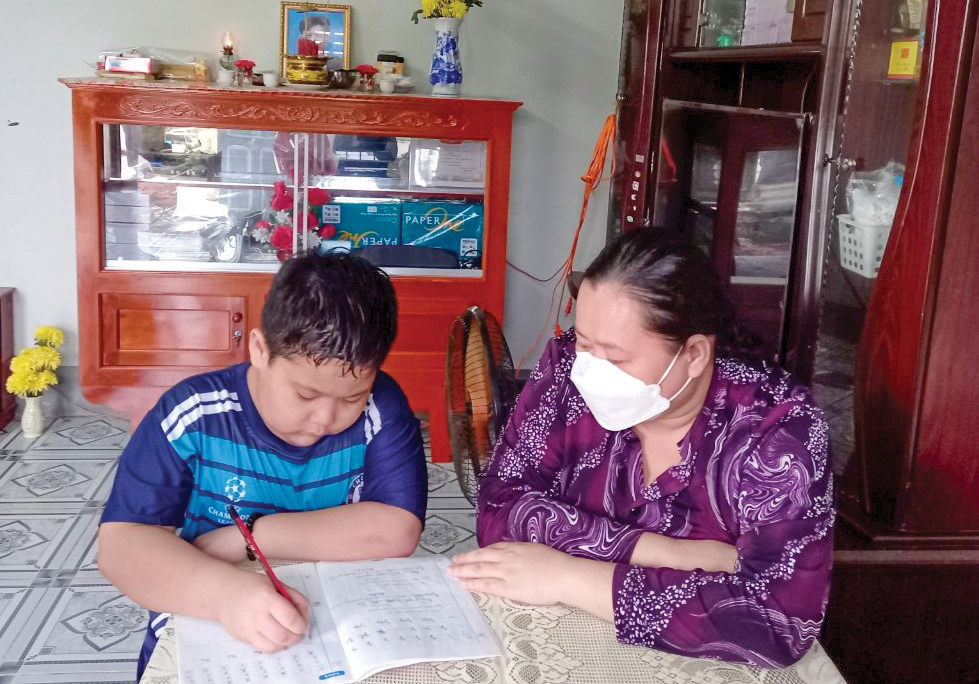 Vượt qua “bão”... Chị Ánh Xuân hướng dẫn con học bài. Ảnh: CTV