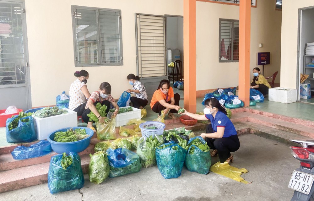 Chị Lê Kim Xuyến, công chức Tư pháp - Hộ tịch thị trấn Thới Lai, huyện Thới Lai (bên ngoài) phân chia rau củ để phân phát cho người nghèo.