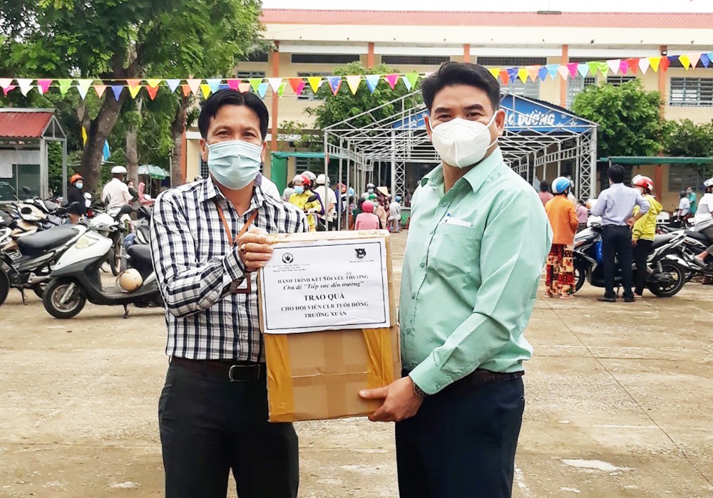 Đại diện Trung tâm CTXH thành phố (bên phải) trao tập cho Ban Chủ nhiệm CLB Tuổi Hồng Trường Xuân.