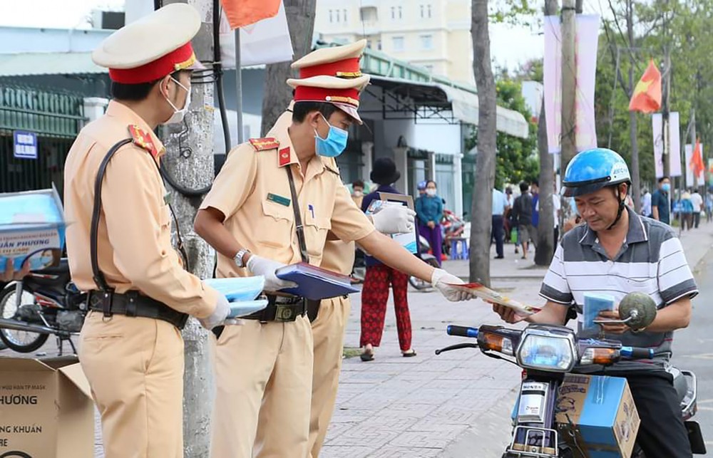Lực lượng Cảnh sát giao thông TP Cần Thơ phát khẩu trang và tờ rơi tuyên truyền người dân chấp hành quy định pháp luật về giao thông.