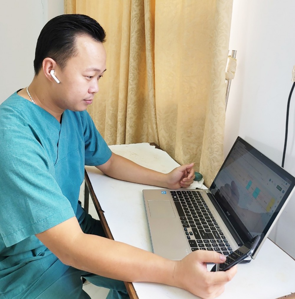 BS Lý Việt Khoa, Trưởng nhóm Thầy thuốc hỗ trợ F0 điều trị tại nhà ở huyện Phong Điền thăm hỏi, tư vấn cho người bệnh. Ảnh do nhân vật cung cấp.