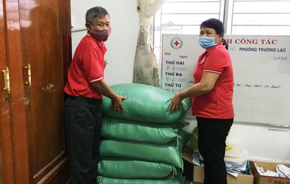 Chú Tám Ánh (bên trái) phối hợp vận động gạo hỗ trợ hoàn cảnh nghèo khó, neo đơn.