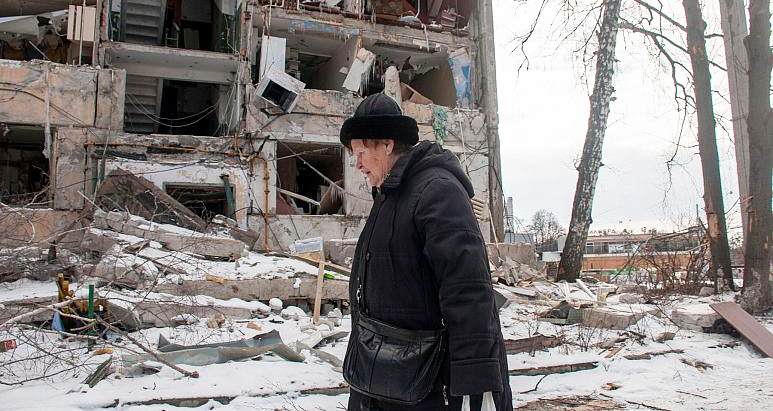 Một phụ nữ đi ngang qua tòa nhà đổ nát vì đạn pháo tại Kharkov ngày 13-3. Ảnh: AP