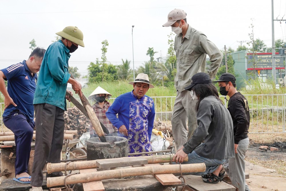 NNƯT Thiều Quang Tùng (người mặc áo dài) cẩn thận kiểm tra trước khi thợ đổ đồng đã nấu vào khuôn đúc.