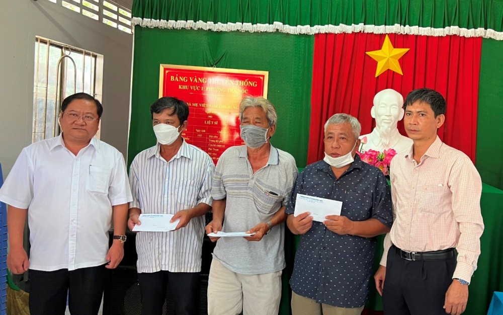 Đồng chí Trần Quốc Vũ (bìa trái) trao tiền hỗ trợ các hộ dân bị ảnh hưởng sạt lở của phường Trà Nóc.