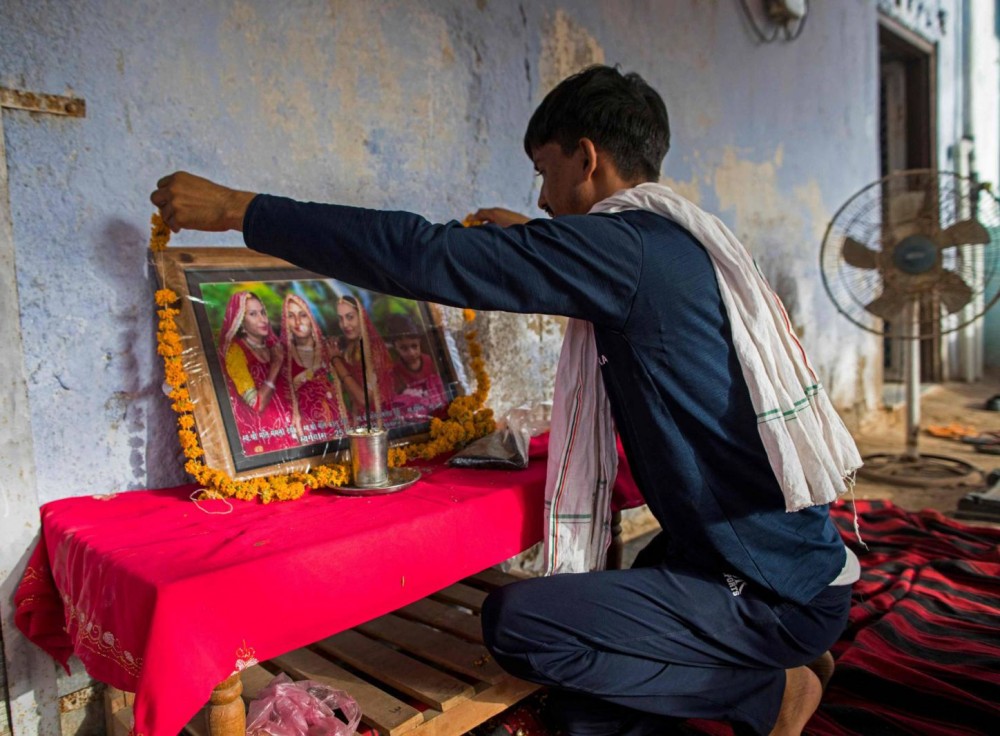 Người đàn ông đặt vòng hoa lên di ảnh ba chị em tự tử vì của hồi môn ở bang Rajasthan. Ảnh: AFP