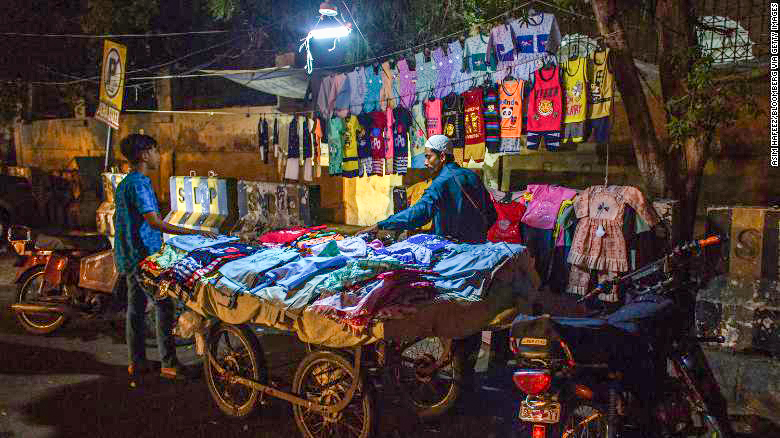 Một người bán vải Pakistan dưới ánh sáng được kết nối với một chiếc xe máy. Ảnh: CNN
