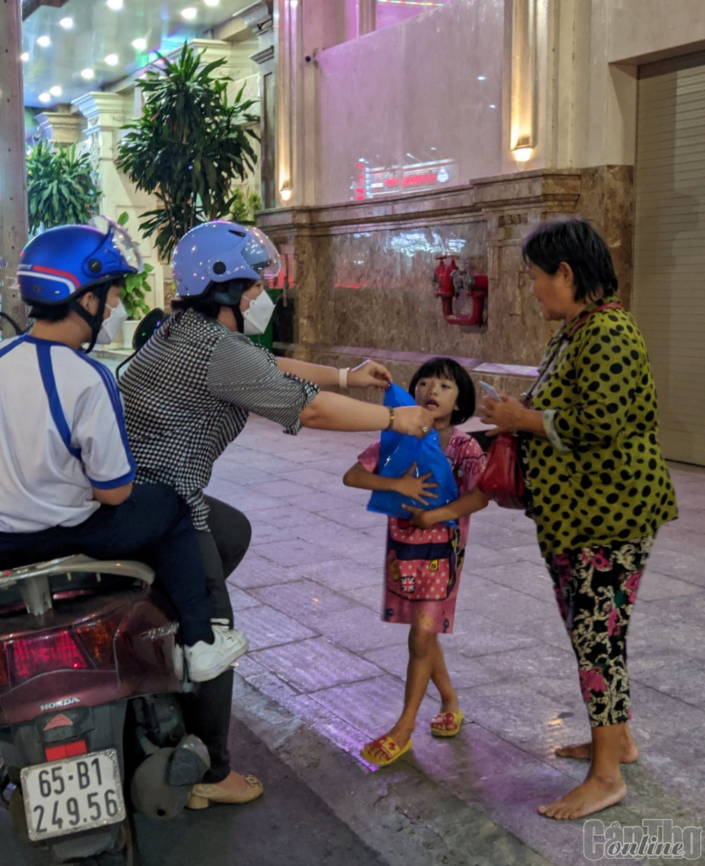 Trung tâm hỗ trợ học sinh, sinh viên TP Cần Thơ làm hơn 3.000 chiếc lồng đèn và vận động 2.000 phần quà tặng thiếu nhi có hoàn cảnh đặc biệt. Trong ảnh: Một tình nguyện viên của Trung tâm tặng quà cho thiếu nhi bán vé số trên đường phố đêm 9-9.