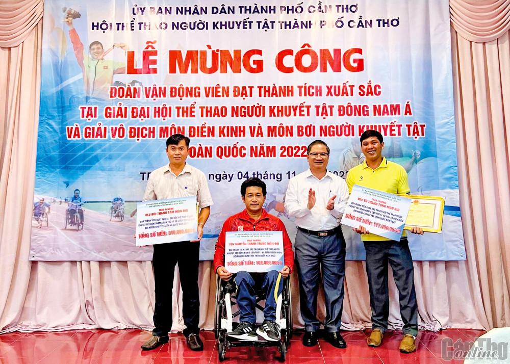 Thanh Tùng (phải) và Thành Trung (ngồi xe) được Chủ tịch UBND TP Cần Thơ Trần Việt Trường tặng thưởng tại lễ mừng công đoàn VĐV người khuyết tật Cần Thơ. Ảnh: Nguyễn Minh
