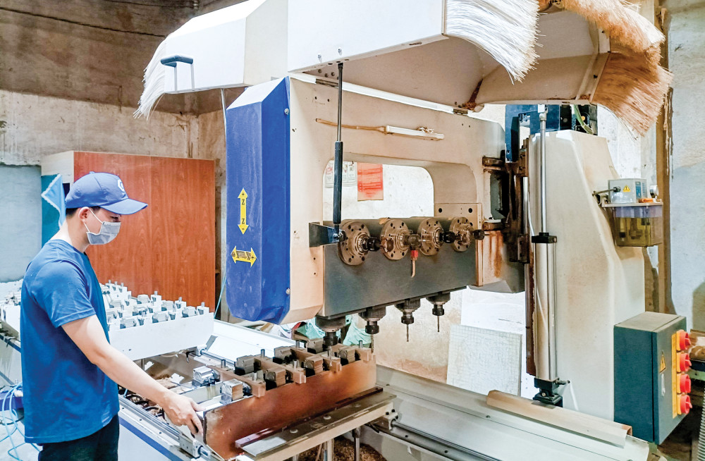 Công nhân Công ty Cổ phần Kiến trúc nội thất Tinh Mộc vận hành máy CNC 5 trục cấp phôi tự động trong gia công sản phẩm gỗ. Ảnh: LỆ THU