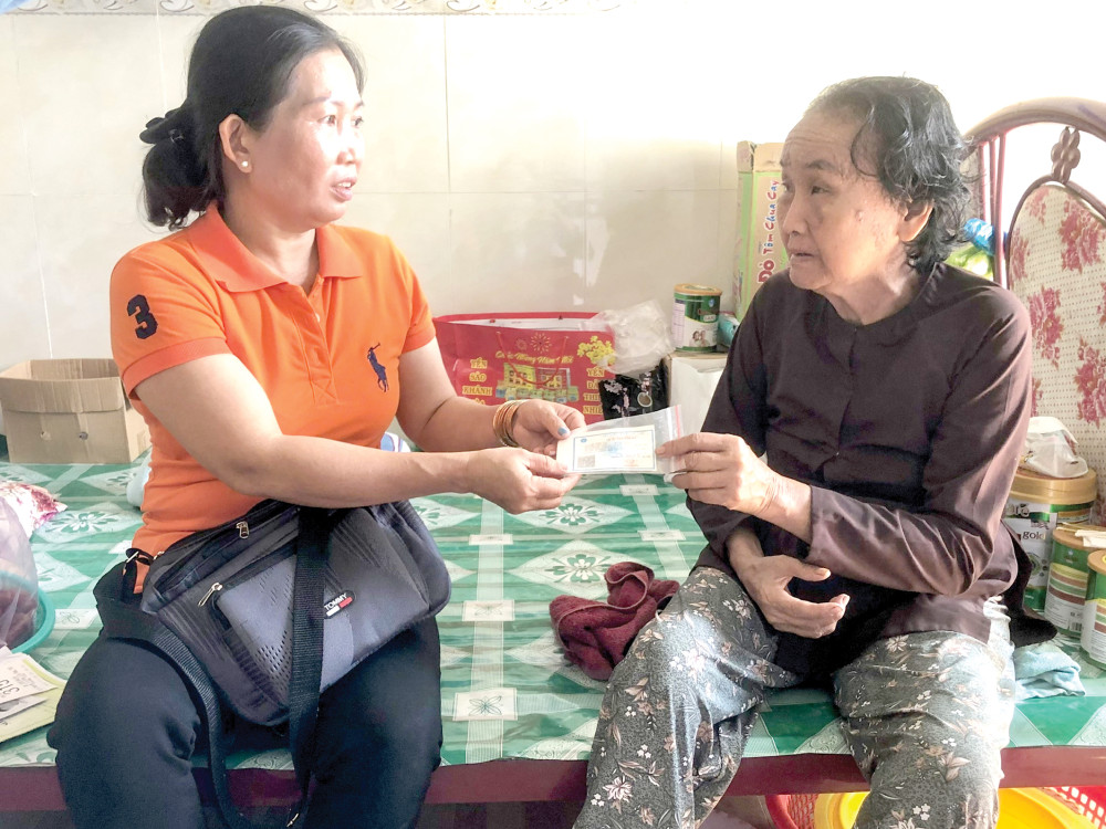 Chị Trần Thị Út Em (bên trái) thăm hỏi, tặng thẻ bảo hiểm y tế cho người dân có hoàn cảnh khó khăn tại khu vực  Phú Thuận.