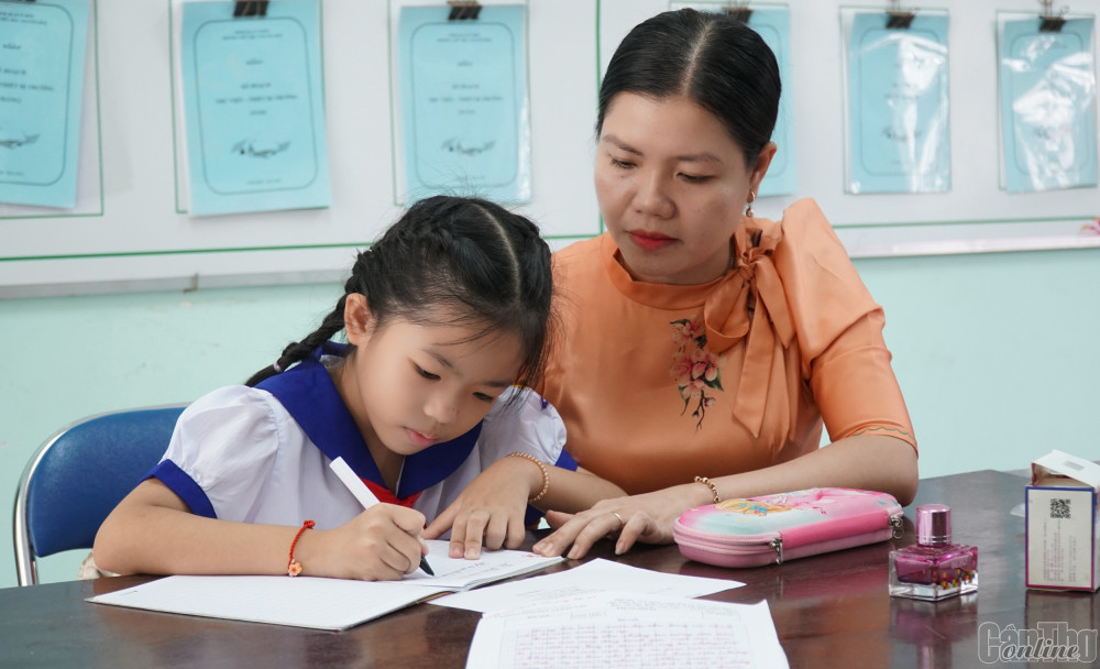 Cô Huỳnh Thị Kim Liên, giáo viên Trường Tiểu học Nguyễn Huệ rèn chữ cho em Đỗ Quỳnh Hương tại trường.