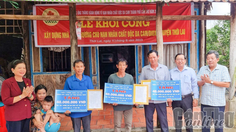 Bà Võ Thị Thanh Nga, Chủ tịch Hội NNCĐDC/dioxin TP Cần Thơ (bìa trái) trao bảng tượng trưng hỗ trợ tiền xây dựng nhà ở cho các nạn nhân ở huyện Thới Lai.
