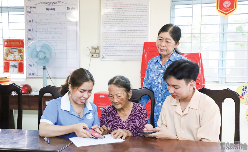 Chị Hà Thị Như Ngọc, Chi hội trưởng Chi hội Phụ nữ ấp Nhơn Bình, xã Nhơn Ái (bìa trái) hướng dẫn người dân kích hoạt tài khoản định danh điện tử.