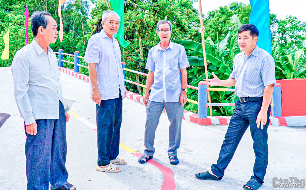 Anh Trần Văn Quí, Bí thư Đảng ủy, Chủ tịch UBND xã Trung An (bìa phải) trao đổi ý kiến với người dân về việc chuẩn bị tổ chức khánh thành cầu Ngã Cạy.