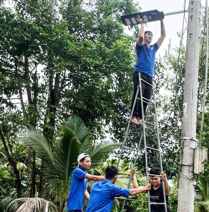 Tuổi trẻ  xã Trung An thi công lắp đặt đèn chiếu sáng công cộng tại rạch Xẻo Cách, giúp người dân đi lại thuận lợi vào ban đêm.