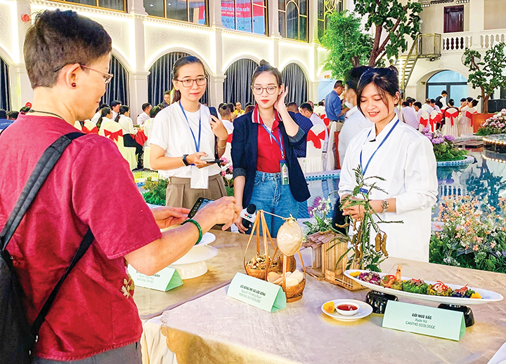 Chị Nguyễn Thị Hồng Đoan (phải) giới thiệu về món gỏi bông me cá lóc đồng.