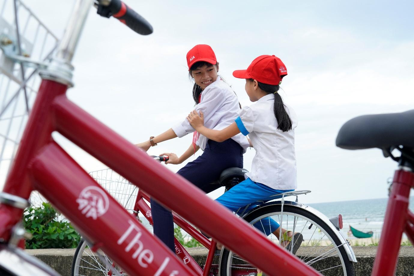 Two girls riding a bikeDescription automatically generated