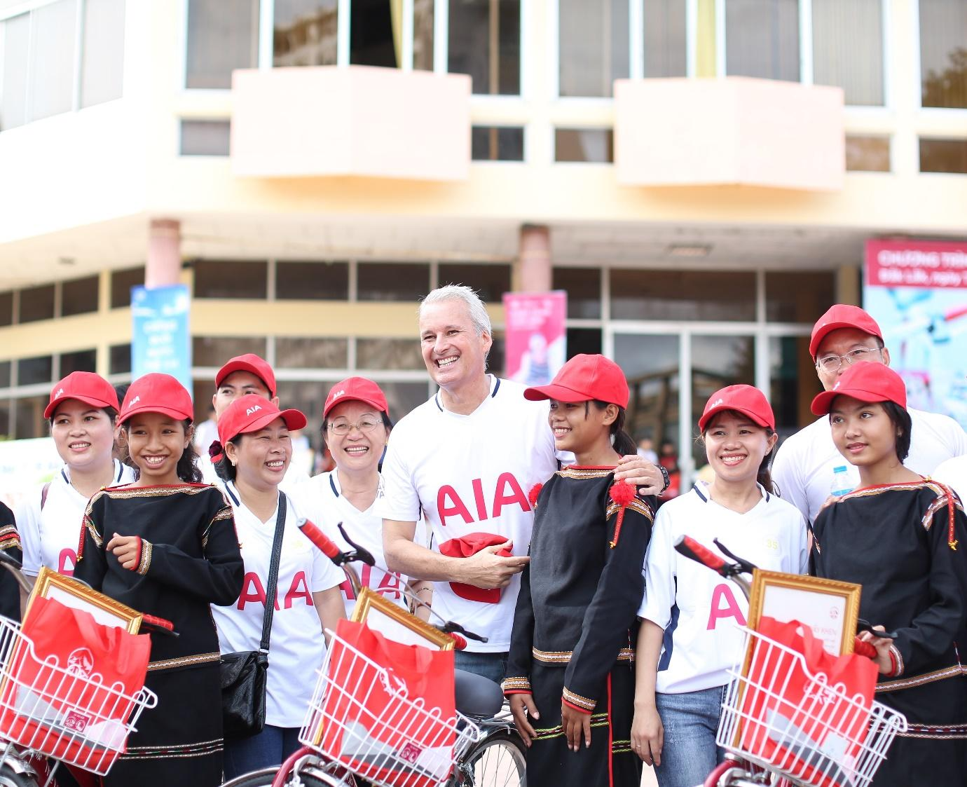 A group of people wearing red hats and holding bicyclesDescription automatically generated