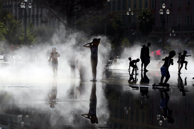 Trẻ em Pháp chơi đùa trong hơi nước ở một vòi phun nước khi thành phố Nice gặp đợt nóng bức, hôm 2-8. Ảnh: Reuters.